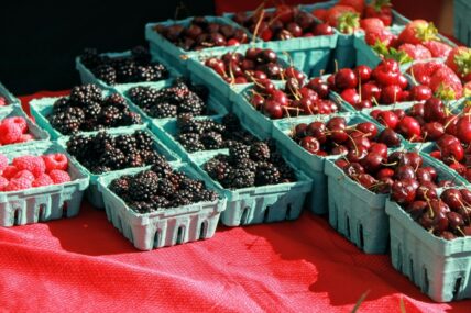 Image of blackberries, cherries, and other berries set on a farmer's market table.