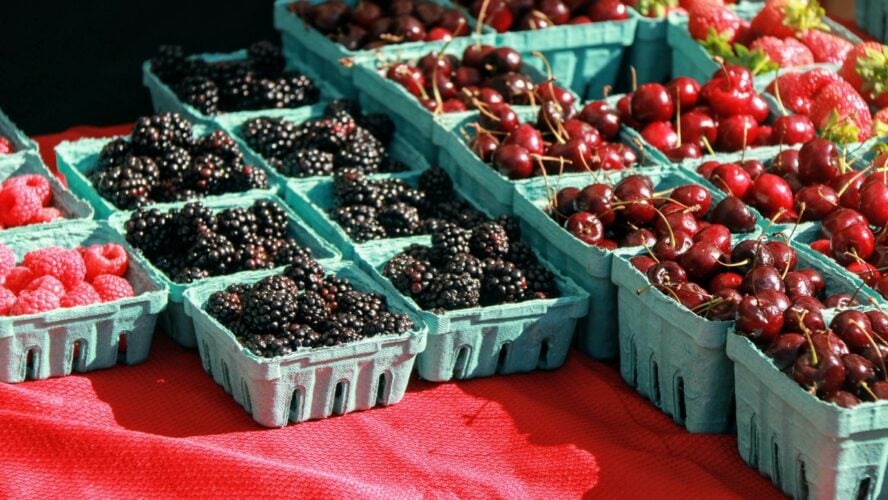 Image of blackberries, cherries, and other berries set on a farmer's market table.