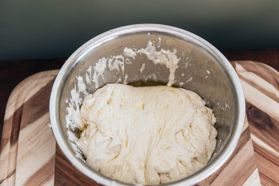 Image of focaccia bread dough in an oiled bowl left to rise.