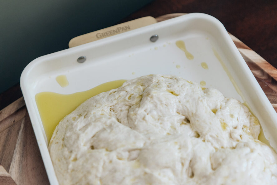 Image of focaccia dough in an oiled pan to prepare for baking.