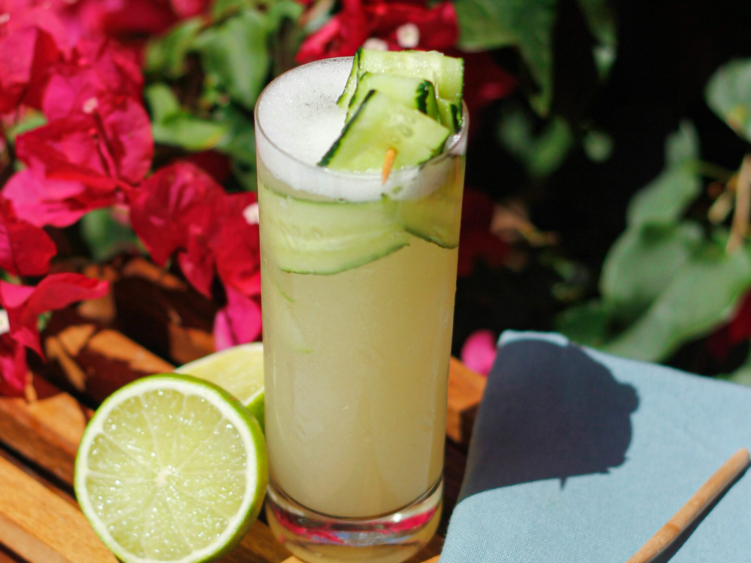 Image of a green juice drink garnished with a ribboned cucumber and lime.