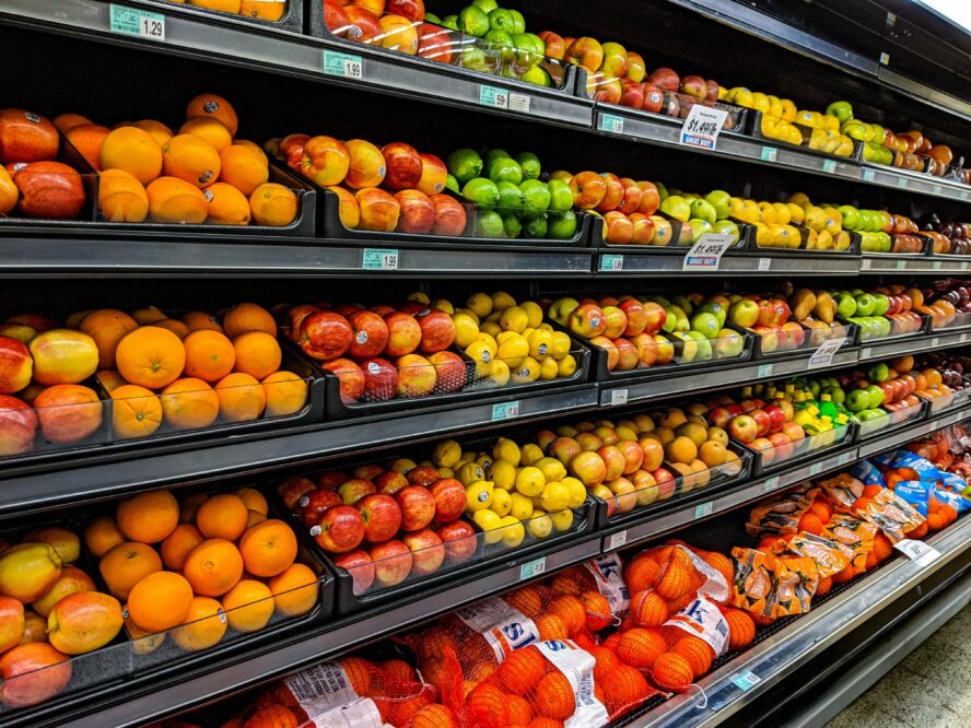Image of a fruit section in a grocery store with apples, oranges, and other fruits.