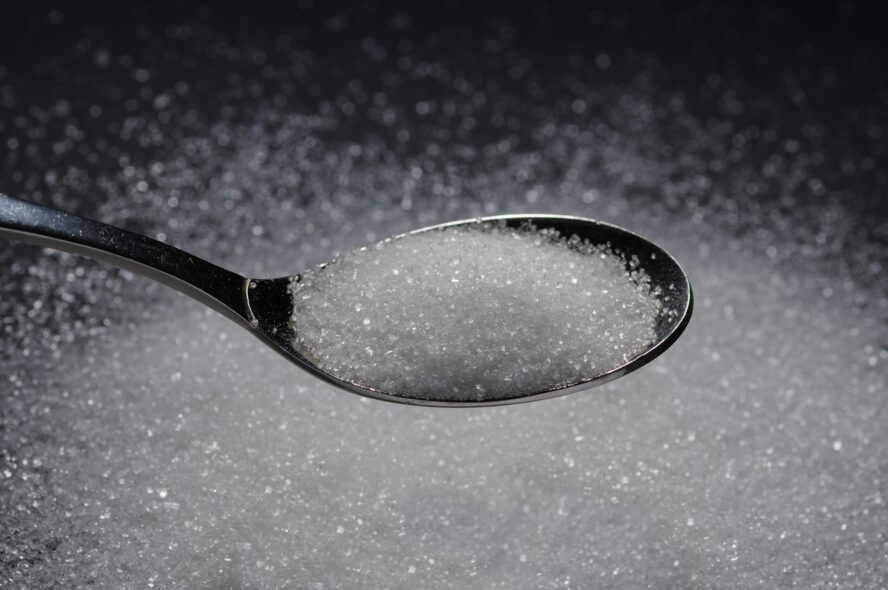 Image of a spoon overflowing with stevia on a black background.