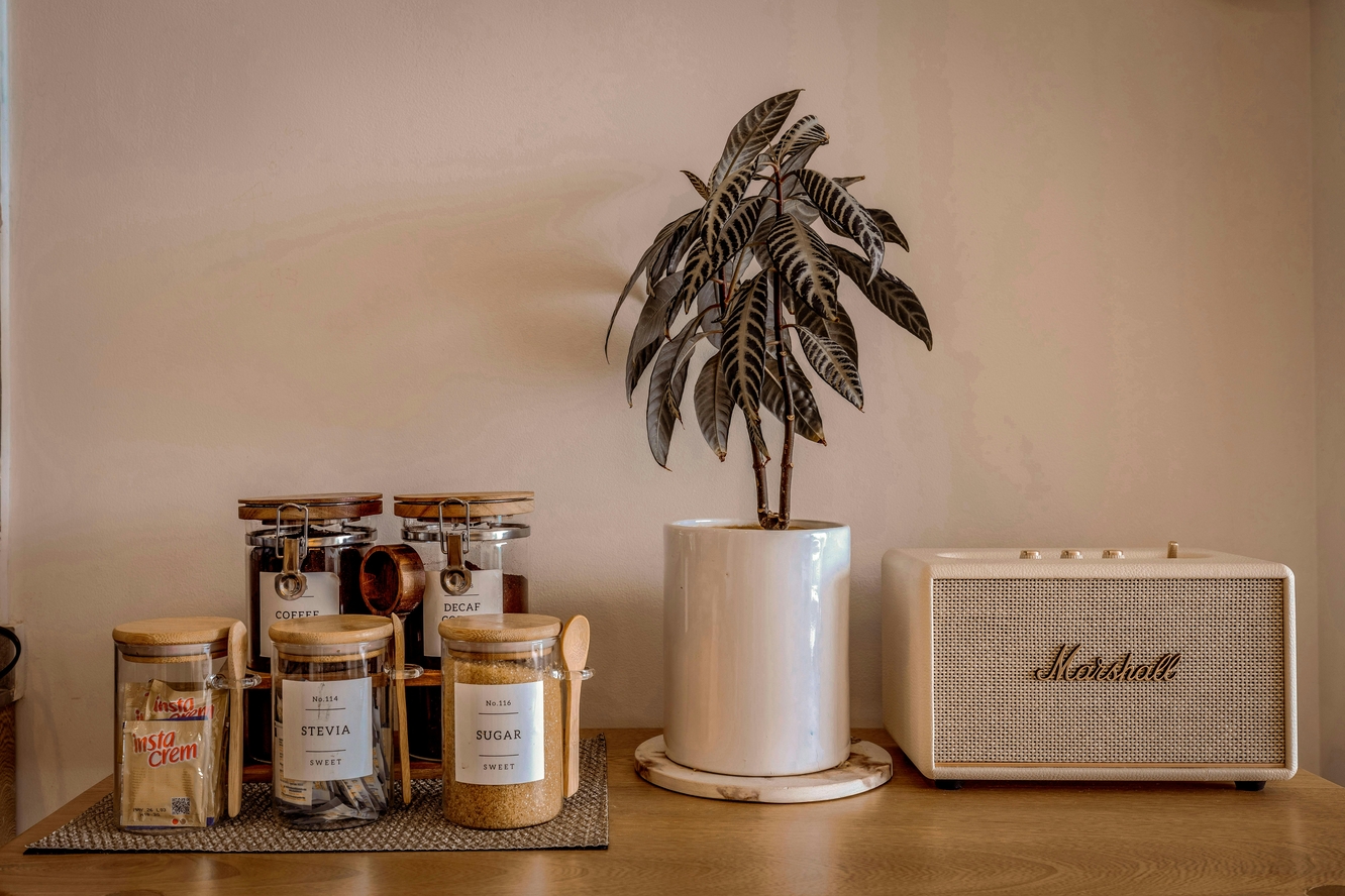 Image of a kitchen counter with little glass jars of sugar, stevia, coffee, and creamer.