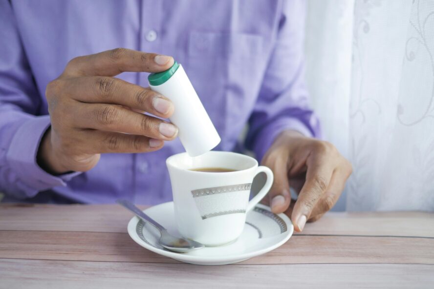 Image of someone adding a sugar substitute into a cup of tea.