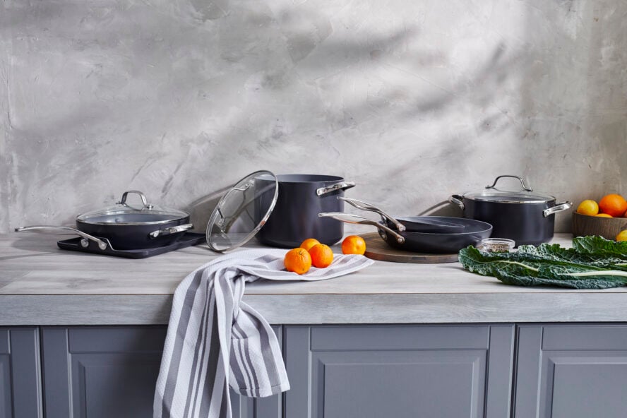 Image of GreenPan Valencia Pro cookware arranged in a gorgeous grey kitchen arranged with some oranges and leafy greens.