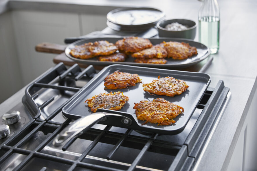 Image of the GreenPan Valencia Pro square griddle pan being used to make latkes on a stovetop.