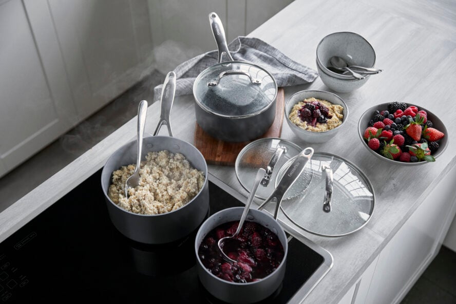 Image of the GreenPan Valencia Pro saucepan set in grey, shown on a stovetop with porridge and berries.