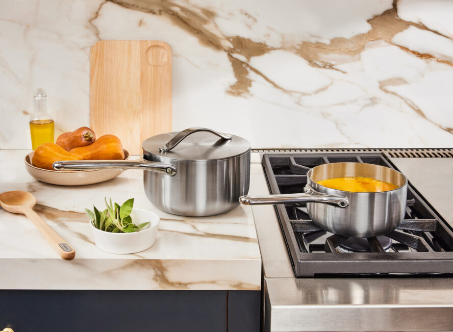Image of two Caraway stainless steel sauce pans shown in a beautiful kitchen.