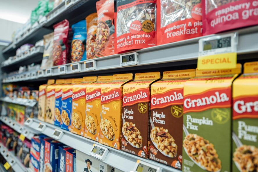 Image of a grocery store aisle stocked with various packages of granola and whole-grain cereals — ultra-processed foods that may seem healthy but can still have negative health effects.