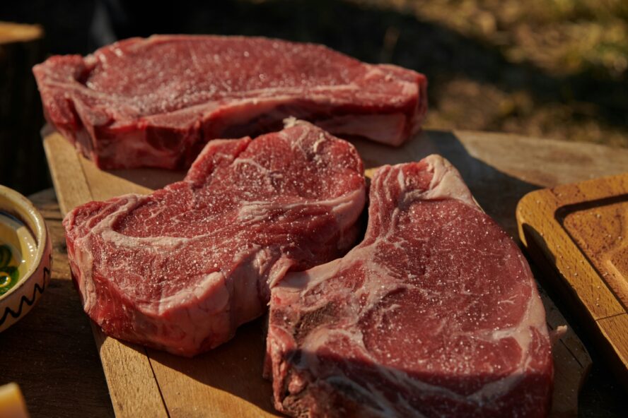 Image of a few raw steaks displayed on a wooden board.