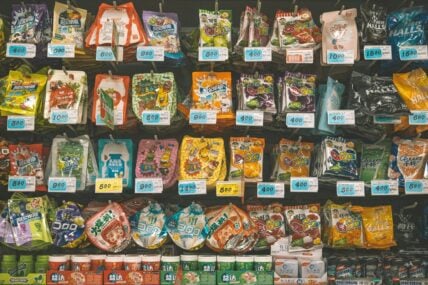 Image of packaged ultra-processed foods like snacks and candies in an aisle at a grocery store.