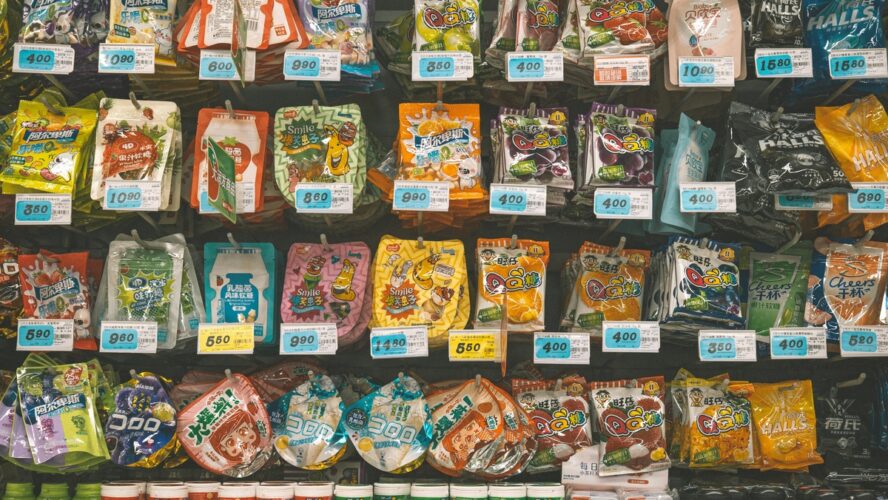 Image of packaged ultra-processed foods like snacks and candies in an aisle at a grocery store.