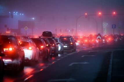 Image of a foggy nighttime street full of car traffic, causing a buildup of vehicle emissions.