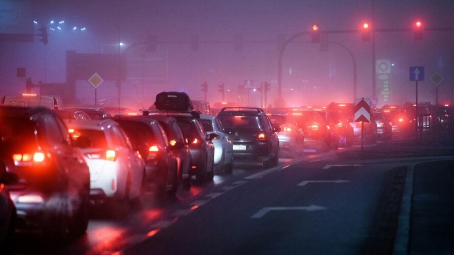 Image of a foggy nighttime street full of car traffic, causing a buildup of vehicle emissions.