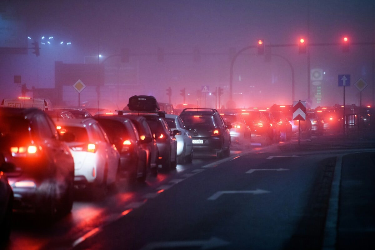 Image of a foggy nighttime street full of car traffic, causing a buildup of vehicle emissions.
