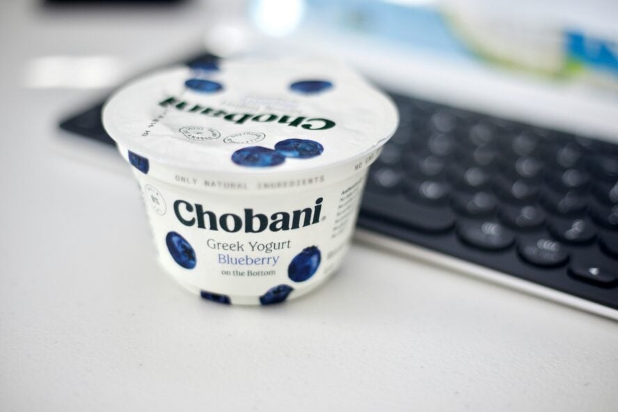 Image of a cup of ultra-processed food, Chobani blueberry yogurt, next to a computer keyboard.