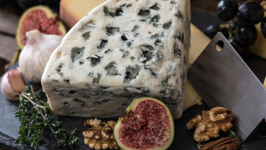 Image of a charcuterie board covered with blue cheese, figs, and nuts.