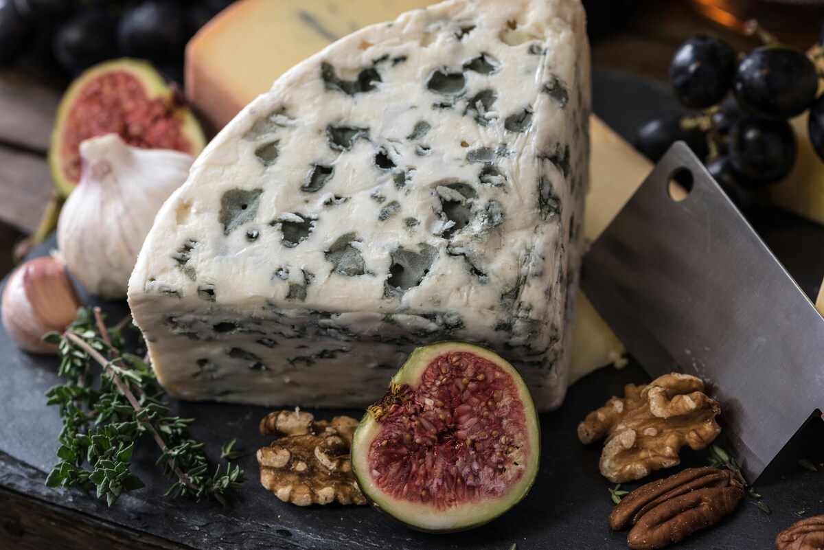 Image of a charcuterie board covered with blue cheese, figs, and nuts.