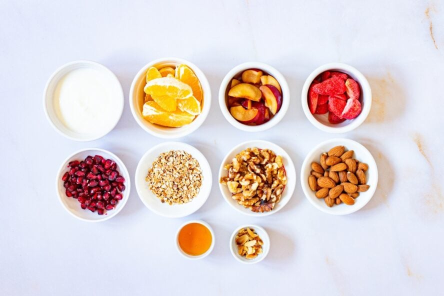 Image of several small white bowls full of high-fiber ingredients for a yogurt bowl.