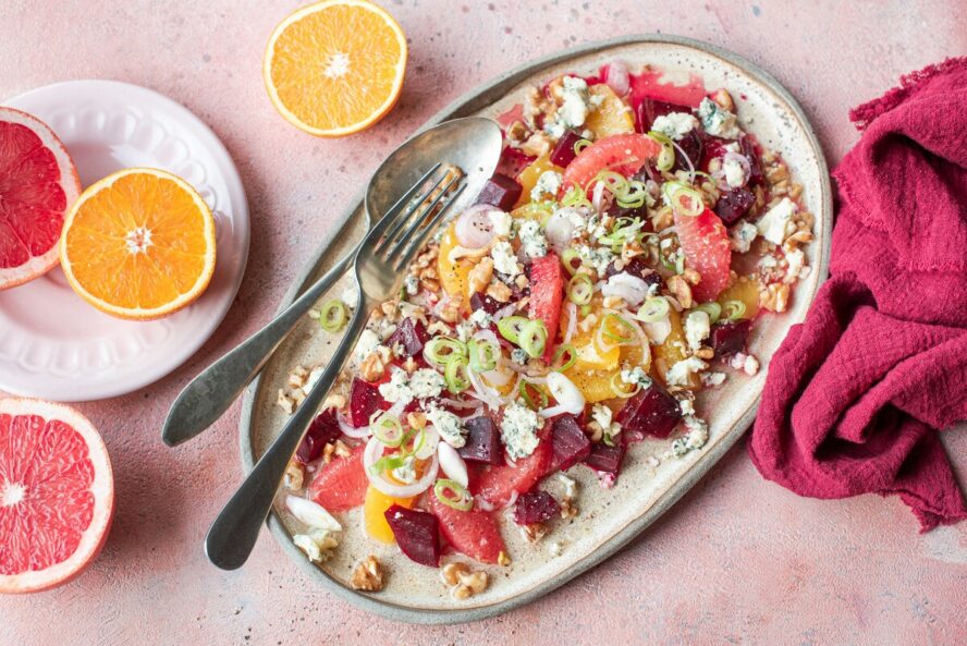 Image of a plate of salad with colorful citrus fruits, beets, walnuts, shallots, and blue cheese.