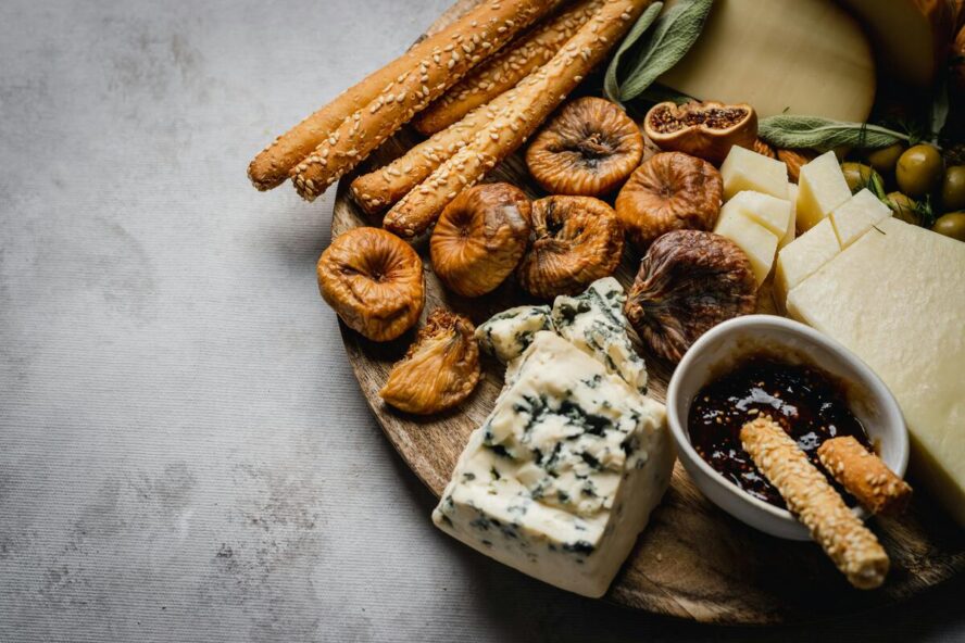 Image of a cheese platter with sesame crackers, blue cheese, jam, and more.