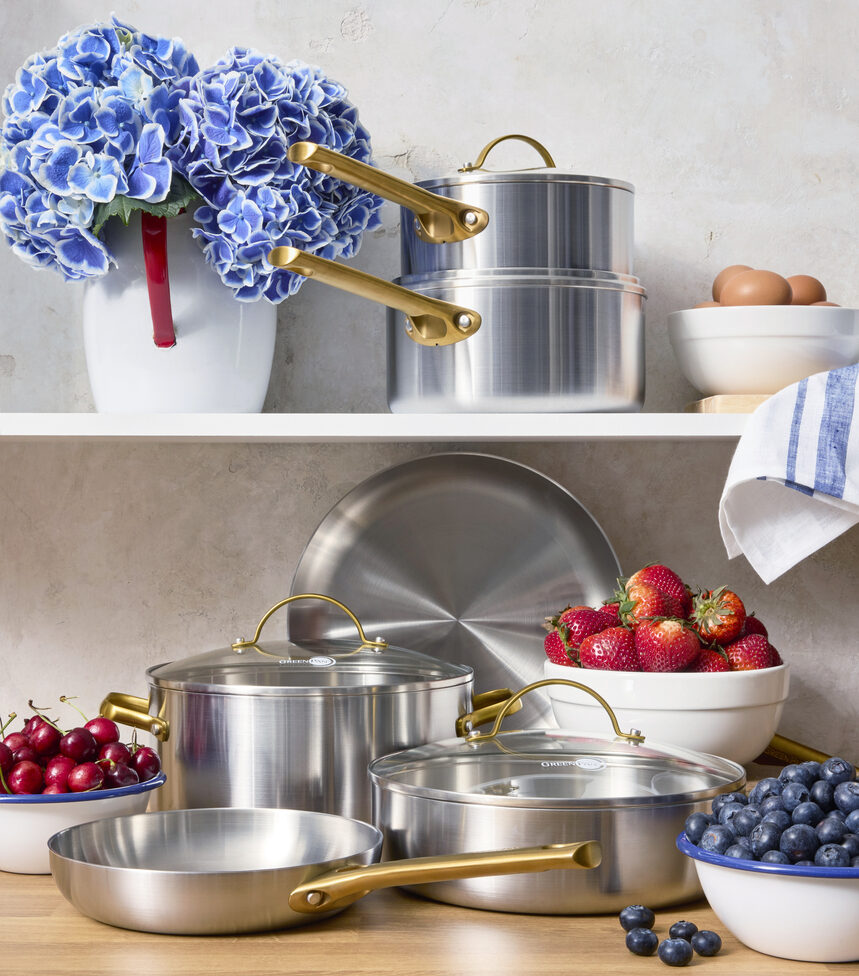 Image of pieces in the GreenPan Reserve Stainless Steel collection displayed in a warm kitchen decorated with blue hydrangeas and strawberries. 