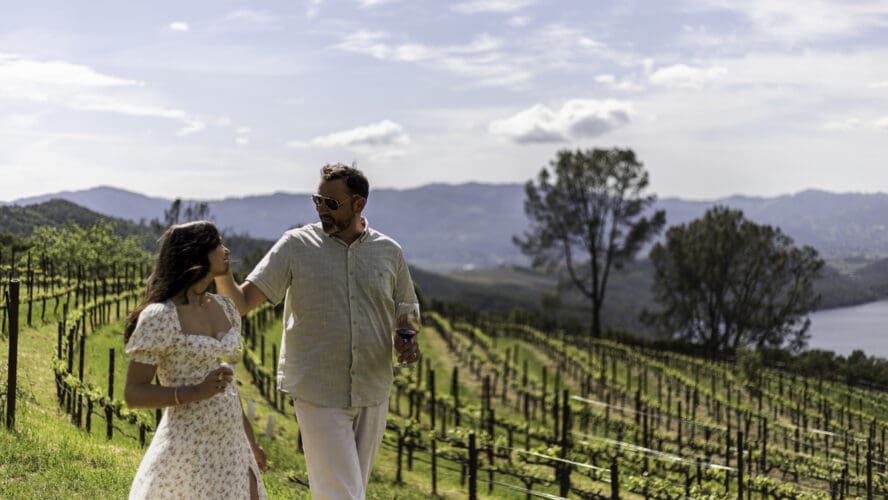 Image of an attractive couple standing in front of the vineyards at the Four Seasons Resort Napa Valley.