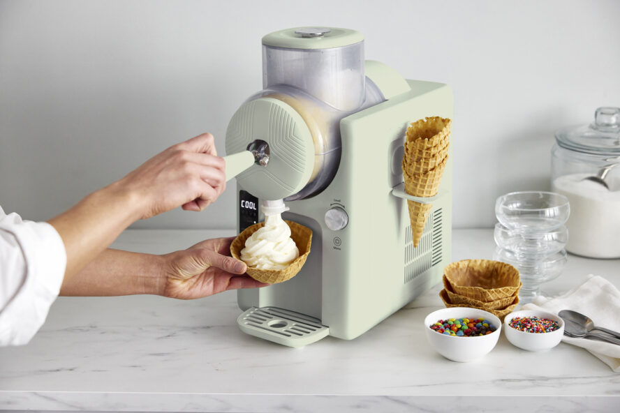 Image of the GreenPan Frost in Pistachio being. used to make vanilla soft serve that is being poured into a waffle cone cup.