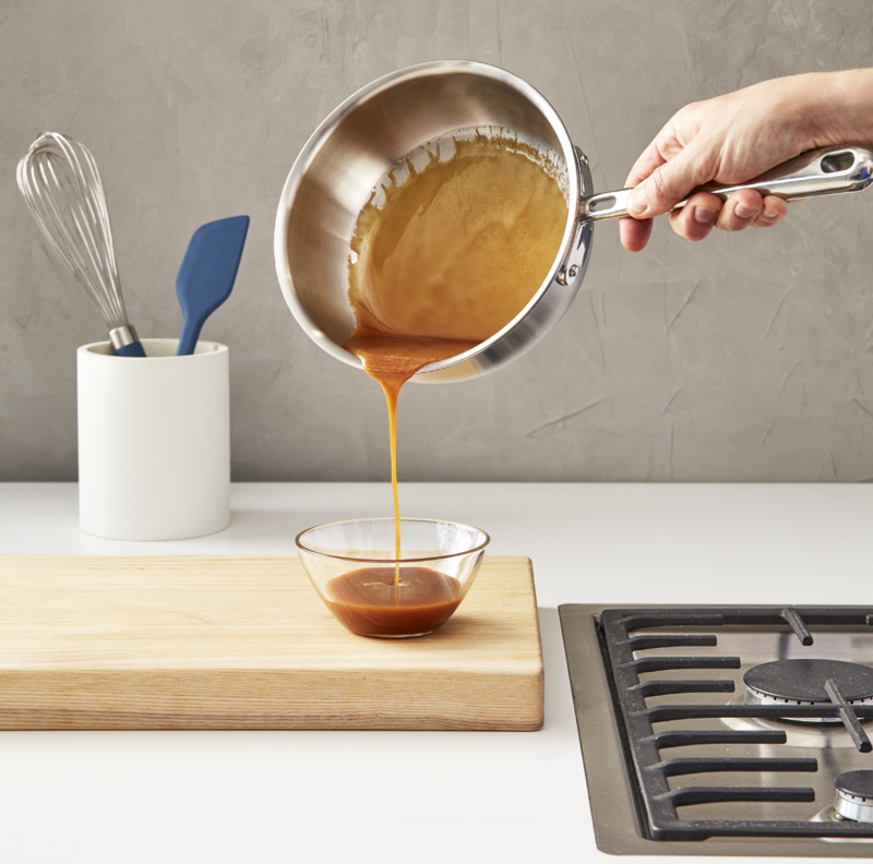 Image of the Misen stainless steel saucier being made to use caramel and pour it into a glass bowl.