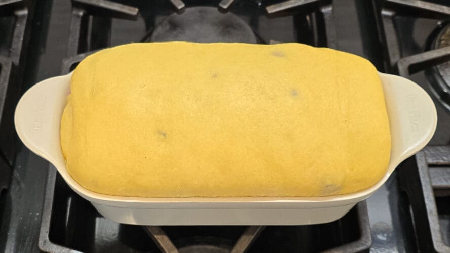 Image of a proofed loaf of brioche rising in an Our Place loaf pan on a stovetop.
