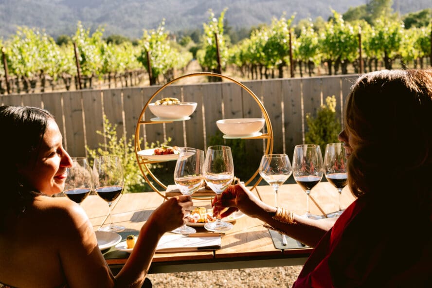 Image of two women sitting at a table at the Clif Family Winery & Farm, clinking their glasses of wine.