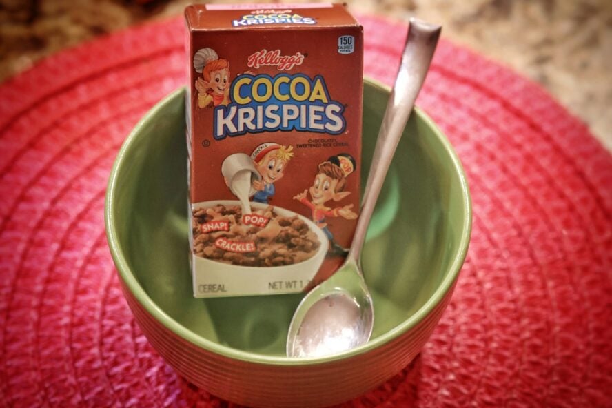 Image of a small box of Kellogg's Cocoa Krispies set in a green bowl with a spoon.