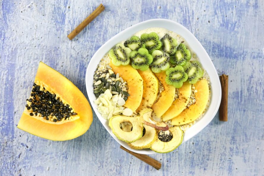 Image of a bowl of oats covered in fruit with lots of fiber, from papaya to kiwi.