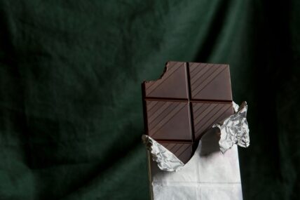 Image of a bar of dark chocolate in silver foil set against a dark green background.