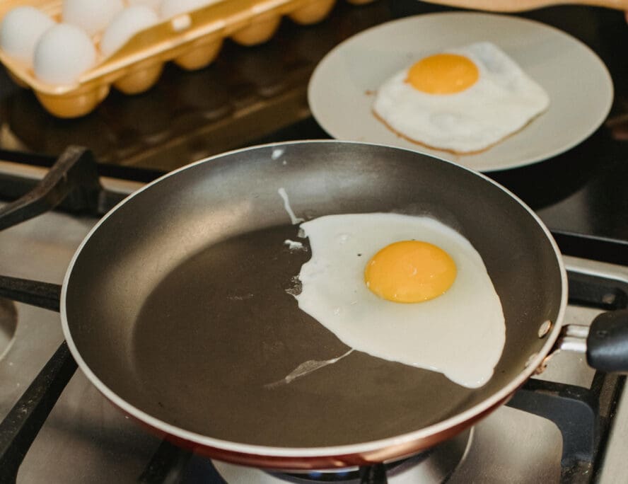 Image of a PTFE nonstick pan being used to fry an egg on a stovetop.
