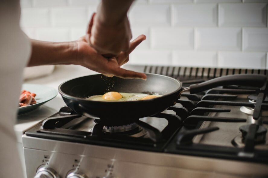 Image of someone cooking fried eggs in a traditional nonstick pan.