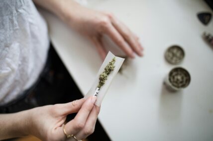 Image of a pair of hands rolling a cannabis joint over a counter.