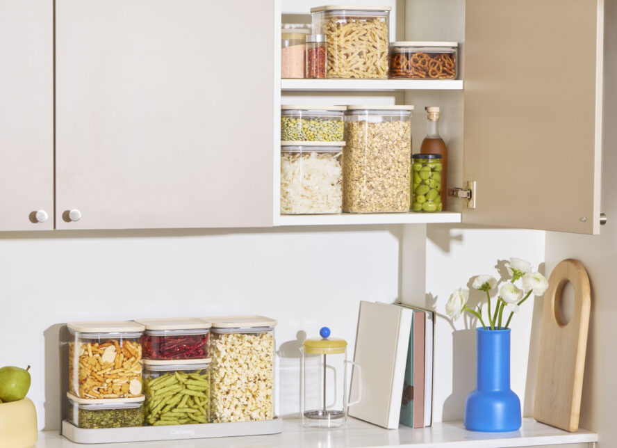 Image of several neatly organized storage areas in a brightly lit kitchen, with many Caraway airtight glass containers used to store various pantry items.