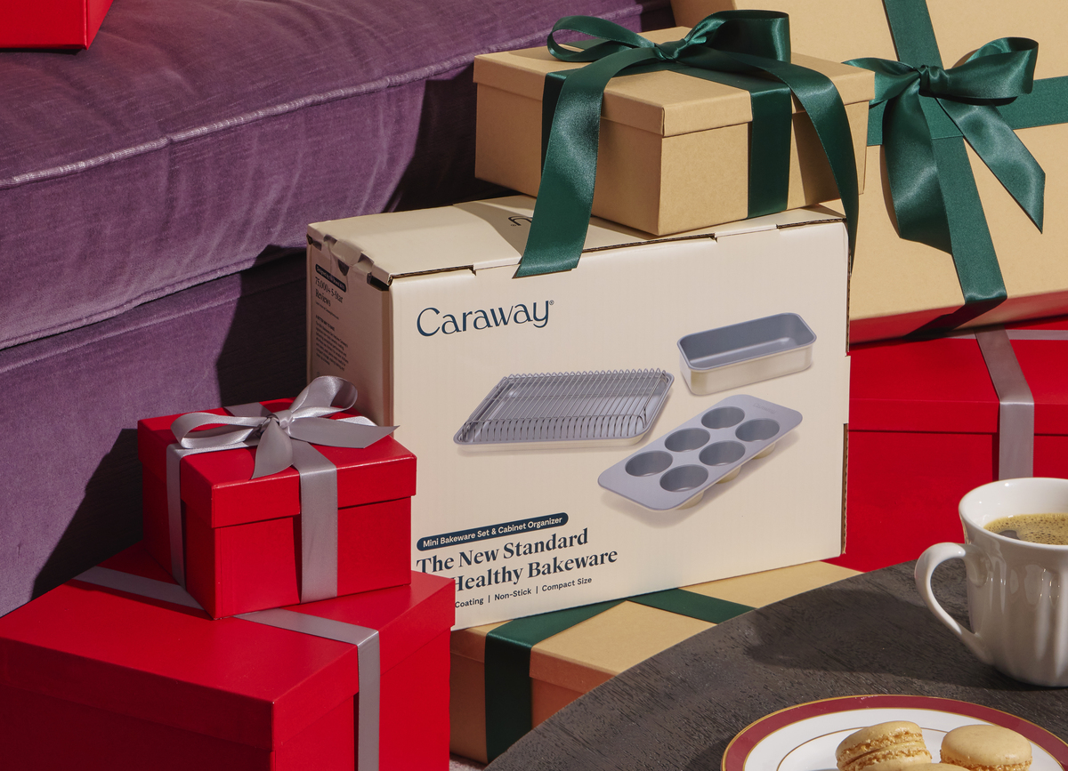 Image of a pile of wrapped gifts, including a Caraway box full of bakeware.