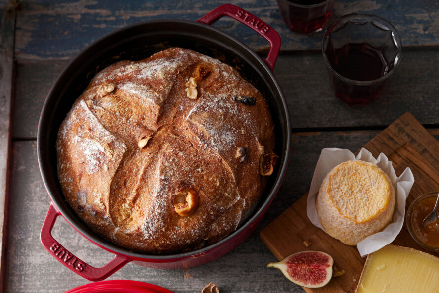 Image of the Staub Round Cocotte in a gorgeous red color being used to bake a loaf of sourdough bread.