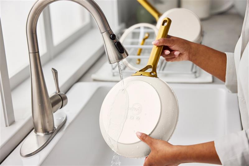 Image of a GreenPan Reserve Pro Stainless Steel fry pan shown being rinsed under running water in the sink.