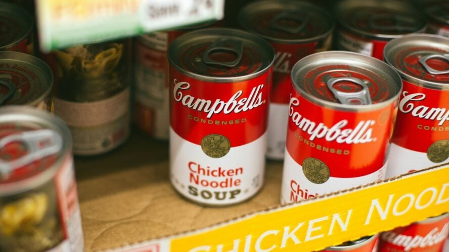 Image of a box on a grocery store shelf filled with Campbell's chicken noodle soup cans.