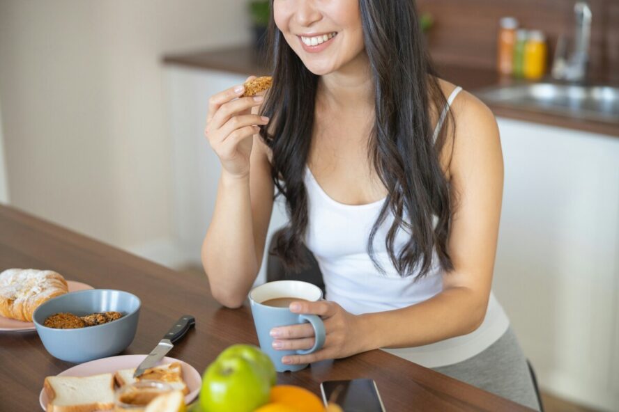 Image of a young woman holding a mug of coffee and enjoying a slow breakfast.