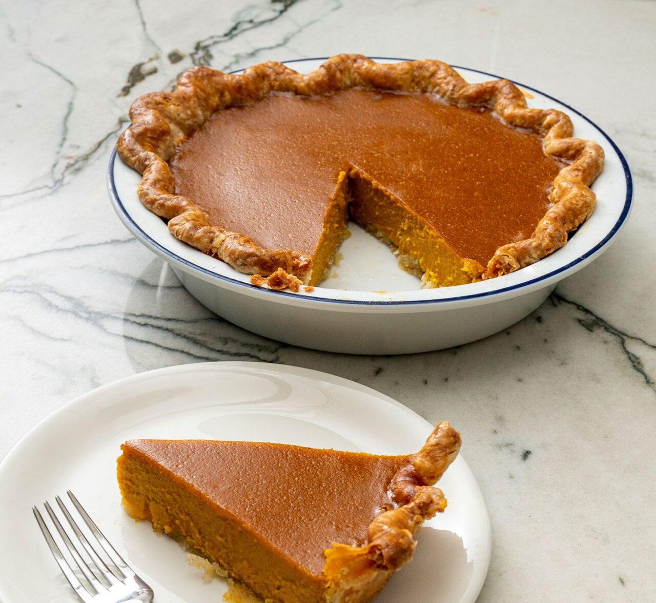 Image of the Made In Pie Serving set with a navy rim being used to serve a slice of pumpkin pie.