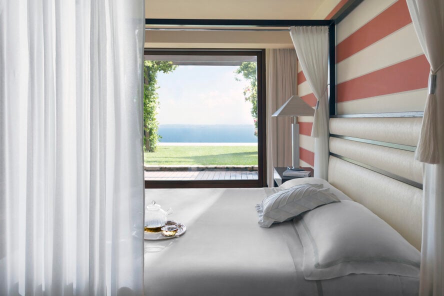 Image of a beautiful bed in the Royal Suite with curtain beside a window overlooking Lake Garda in Italy.