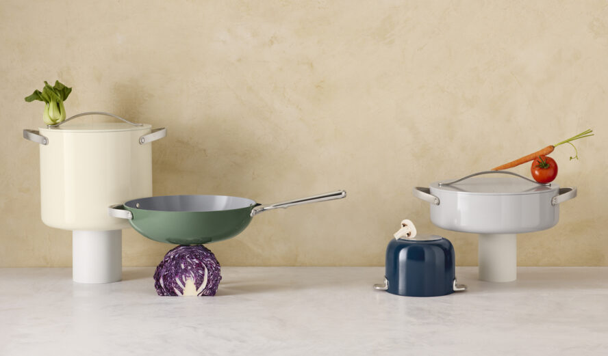 Image of several gorgeous pieces of Caraway cookware displayed like art sculptures in a kitchen against a plaster wall backdrop.