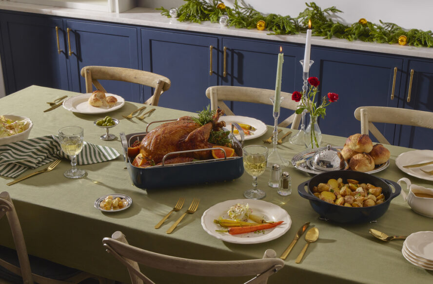 Image of a beautiful holiday tablescape with a turkey in the center and several dishes surrounding it, all cooked in Caraway Cookware.