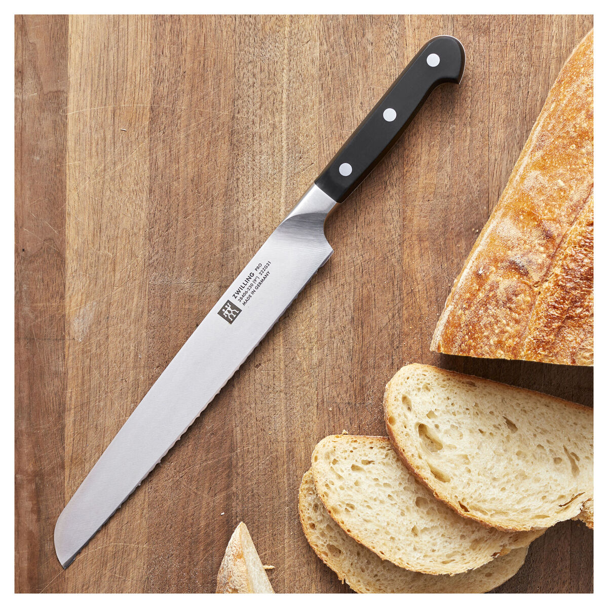 Image of the Zwilling Pro Bread Knife on a wooden slab next to a sliced loaf of sourdough.