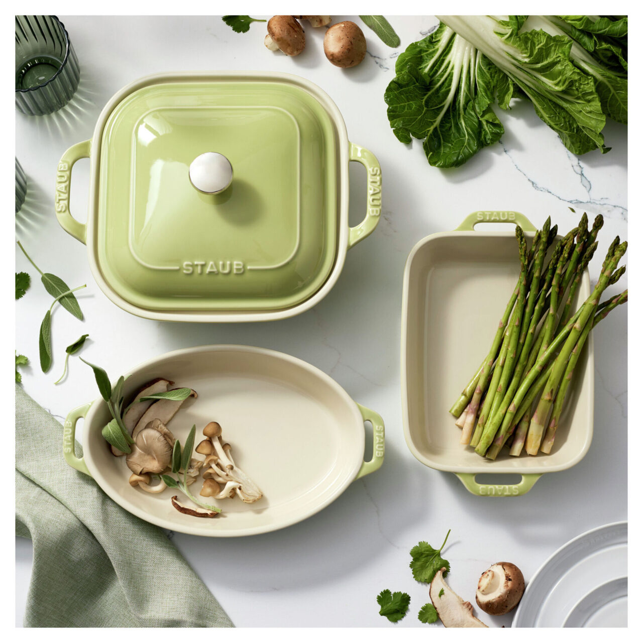 Image of the Staub 4-piece Baking Dish set in light green, shown with fresh ingredients.